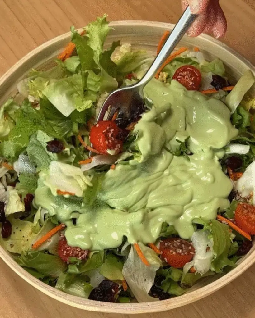 Condimento verde cremoso su insalata fresca con pomodorini e carote